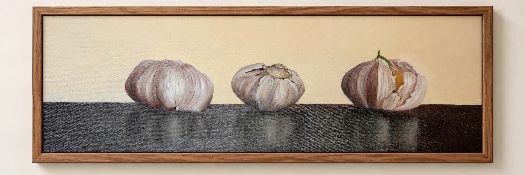 Drie knoflookbollen op een donker vlak, in een brede houten lijst.